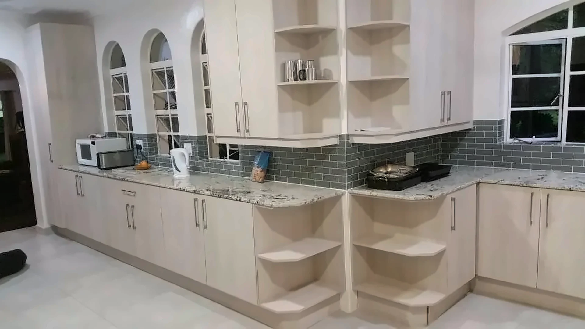 Light timber-finish kitchen with granite worktops and curved corner shelving