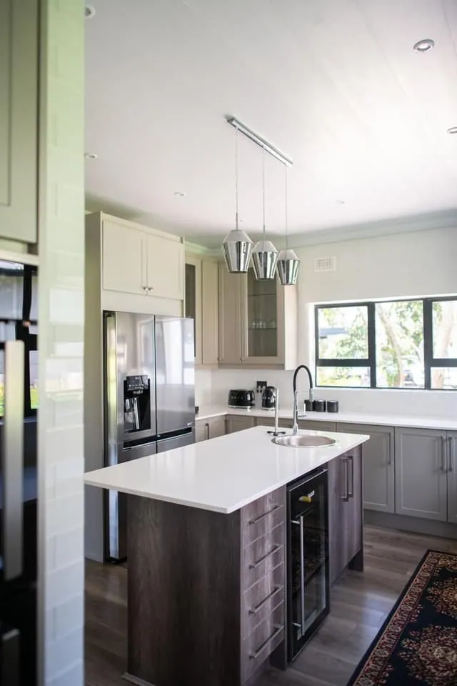 Kitchen with grey subway tiles, stainless canopy and white island