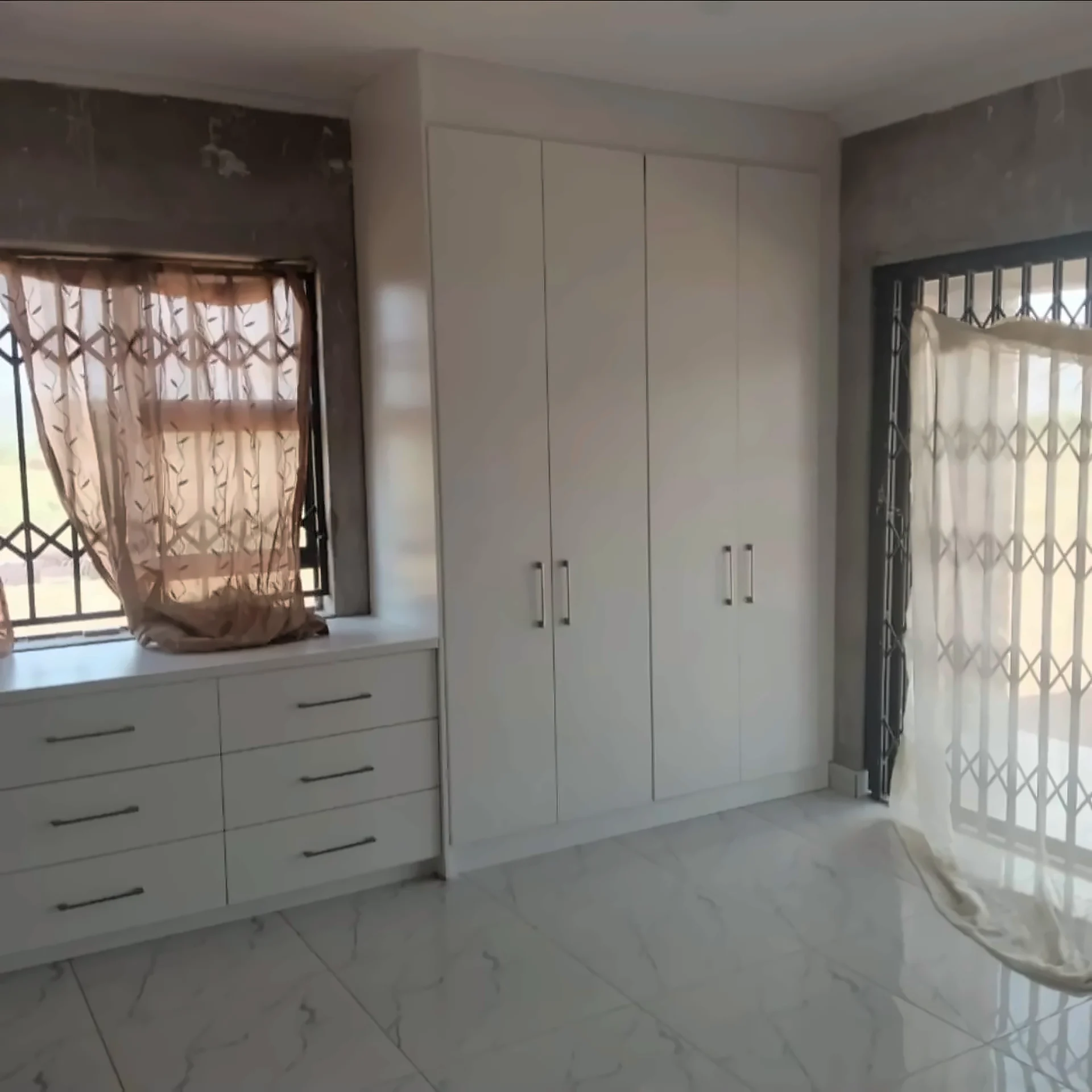Built-in wardrobes flanking a window with a drawer unit beneath