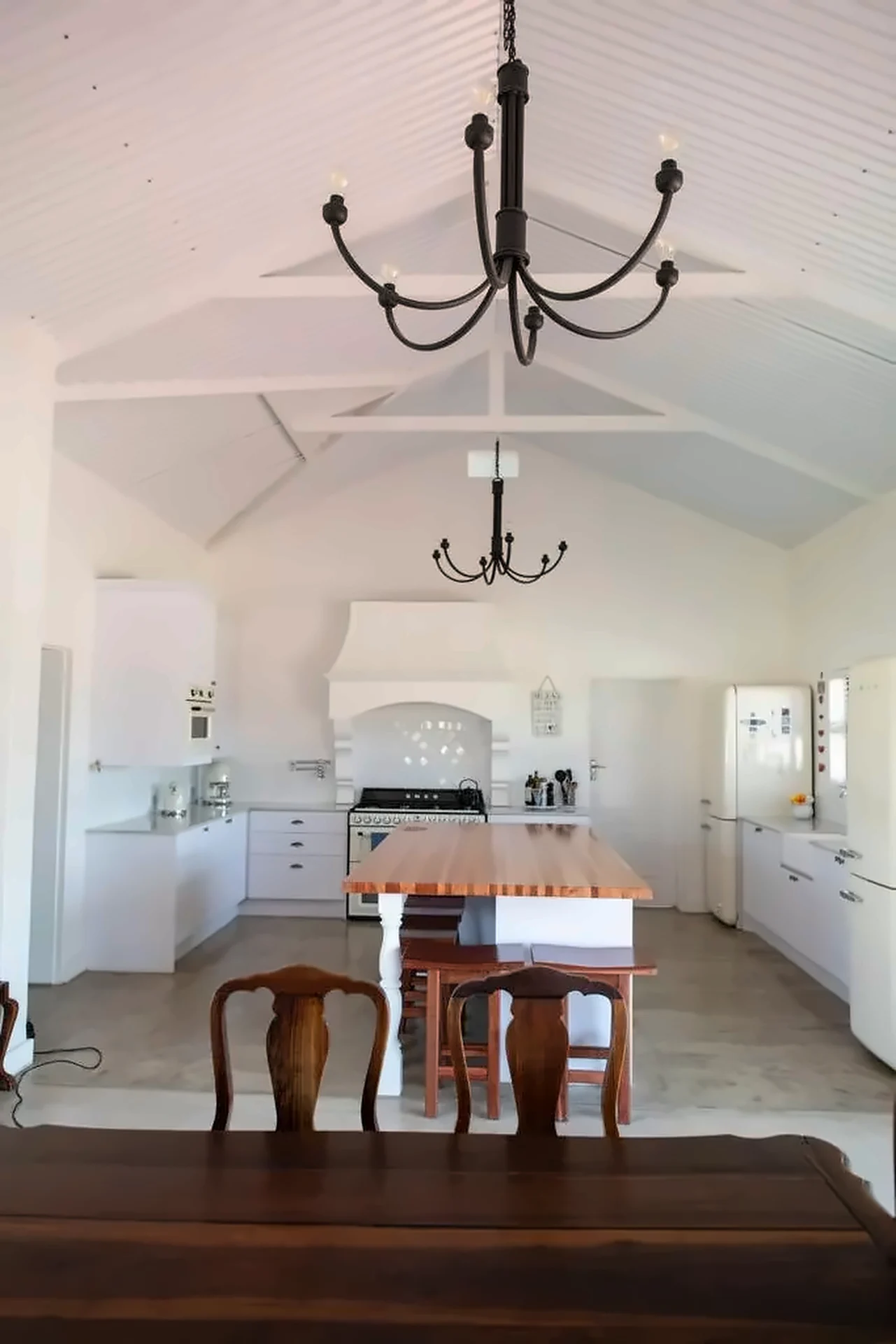 White shaker kitchen with a canopy, range cooker and butcher-block island with basket storage