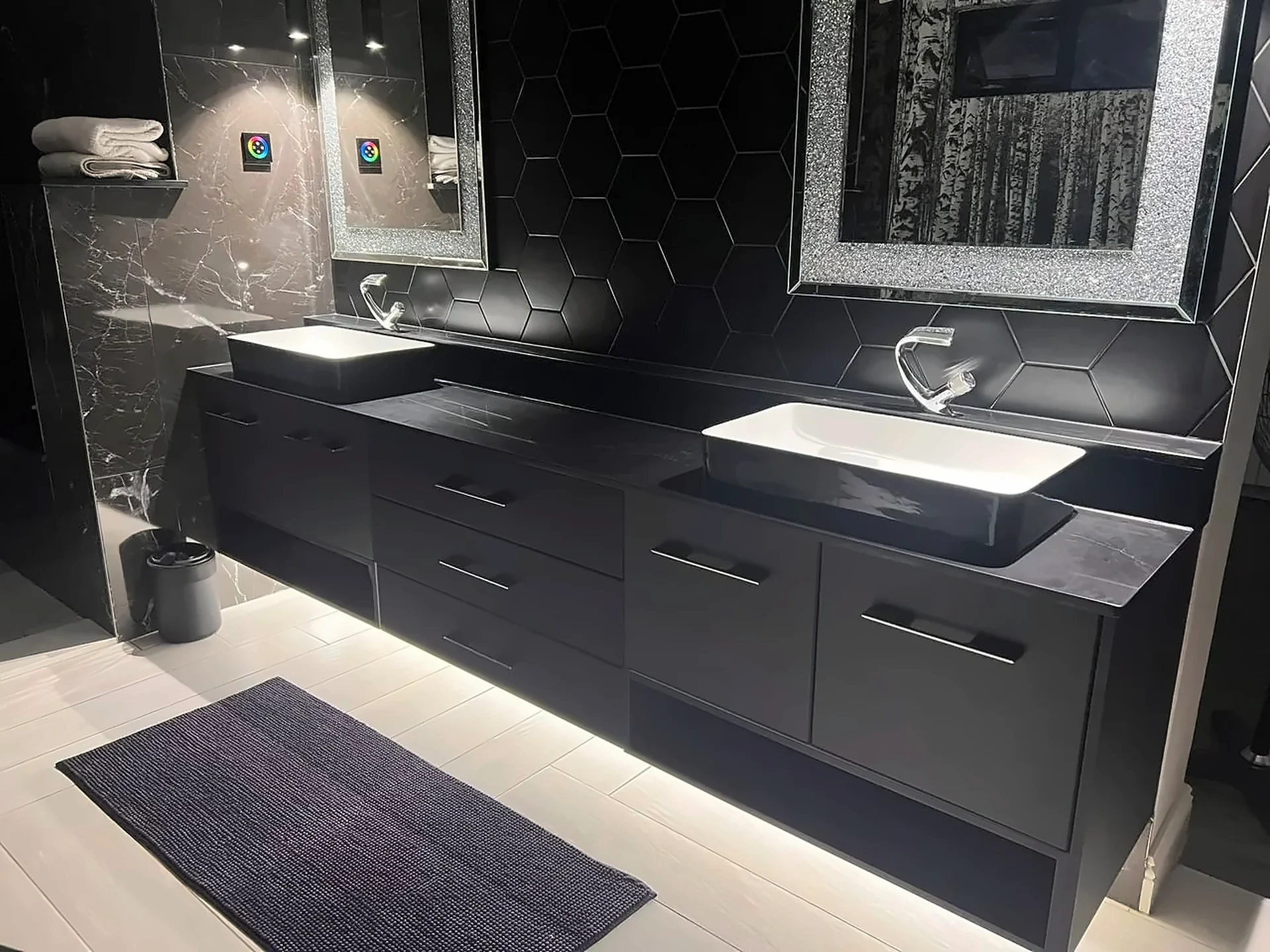 Black vanity units with under-lighting and dark marble walls