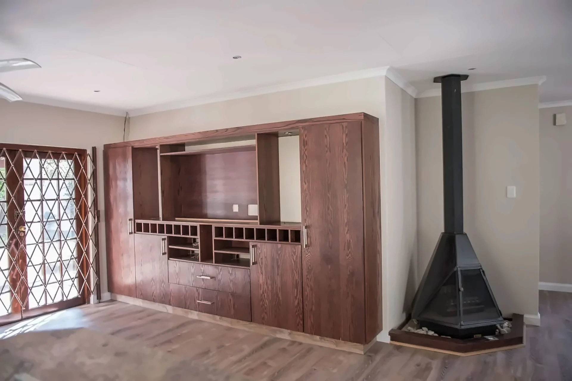 Dark timber wall unit with display niches and wine storage beside a fireplace