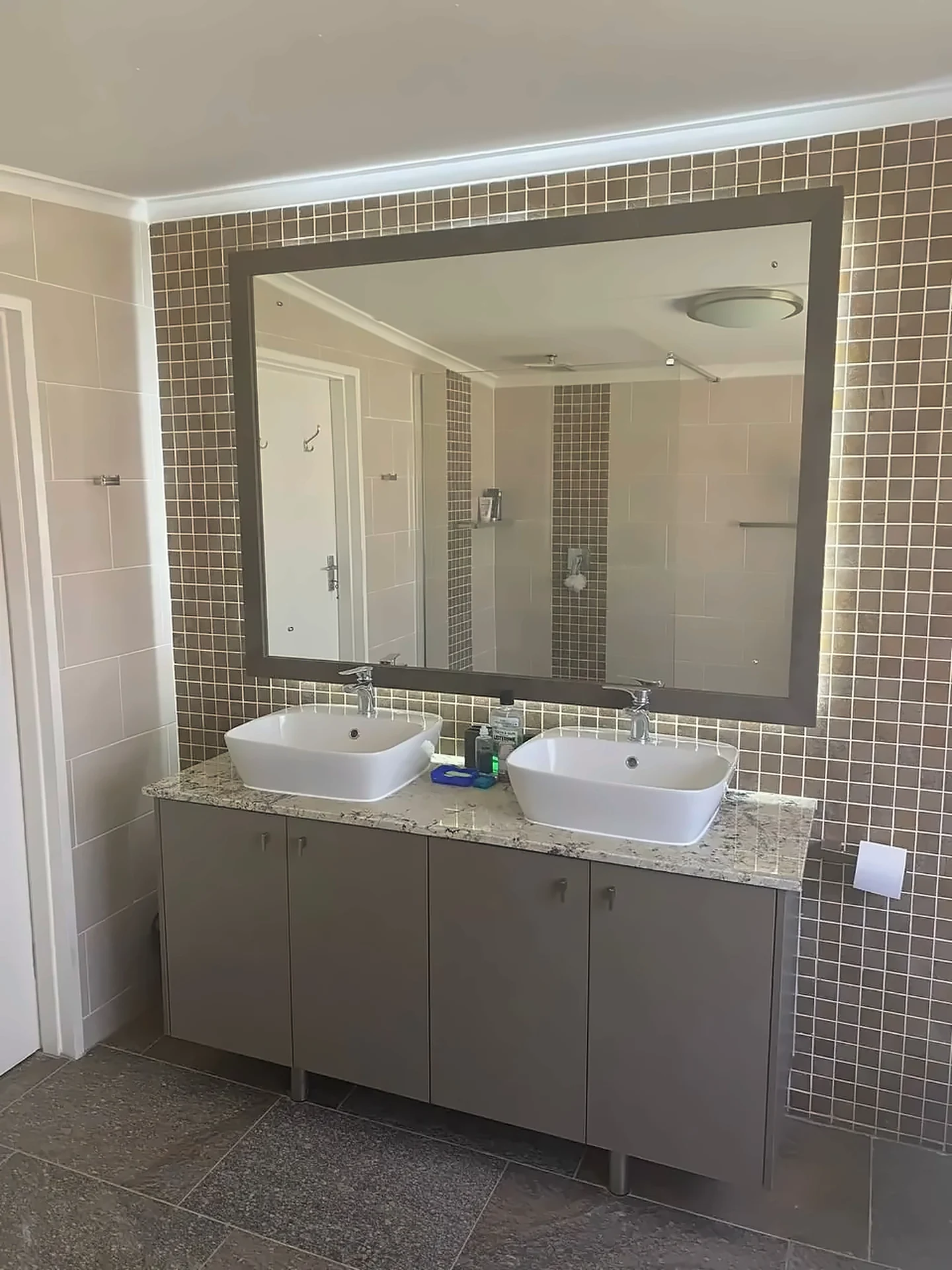 Double-basin vanity with granite top and mosaic-framed mirror