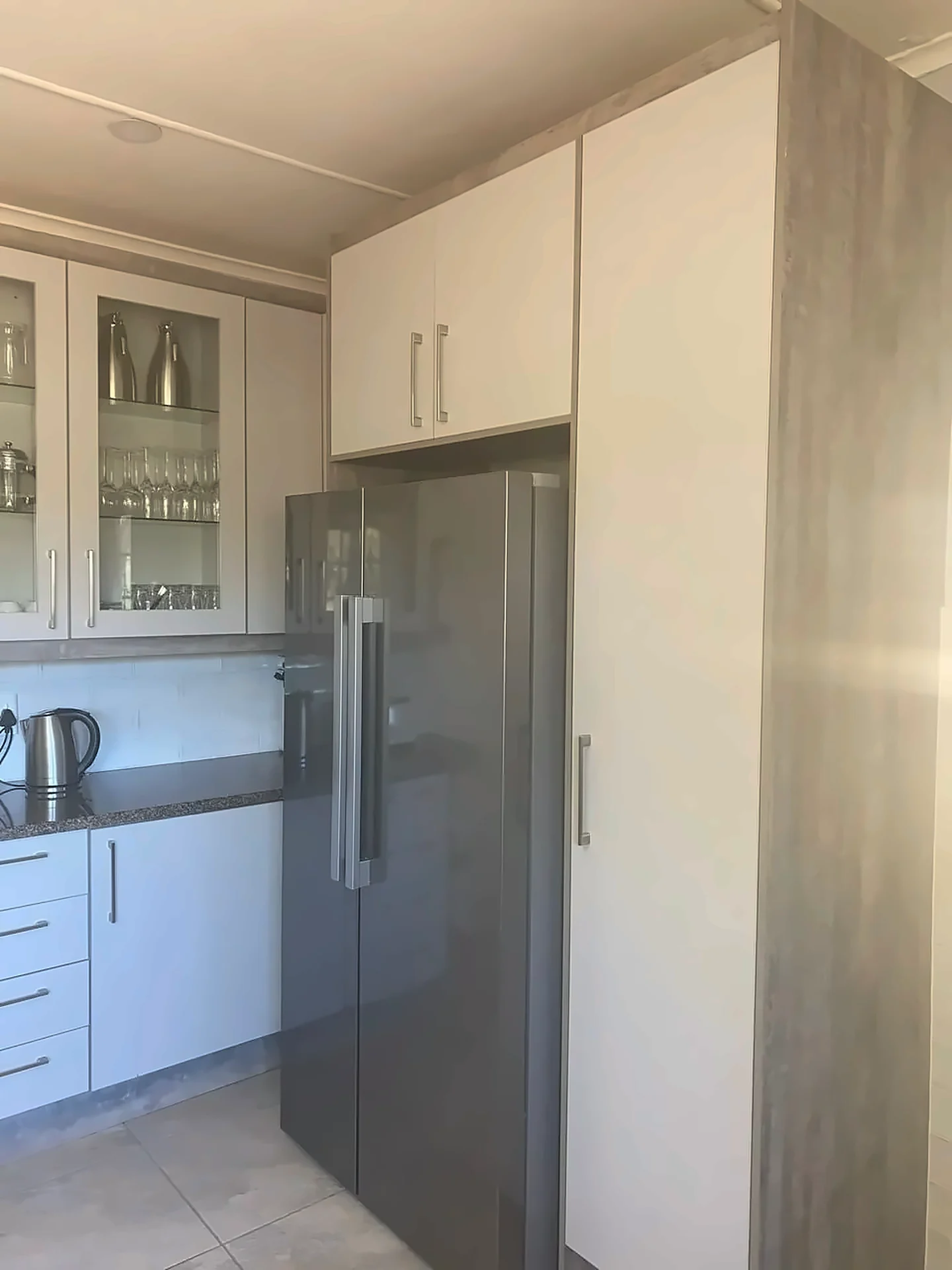 Tall timber-finish units with fridge recess and glazed wall cabinet