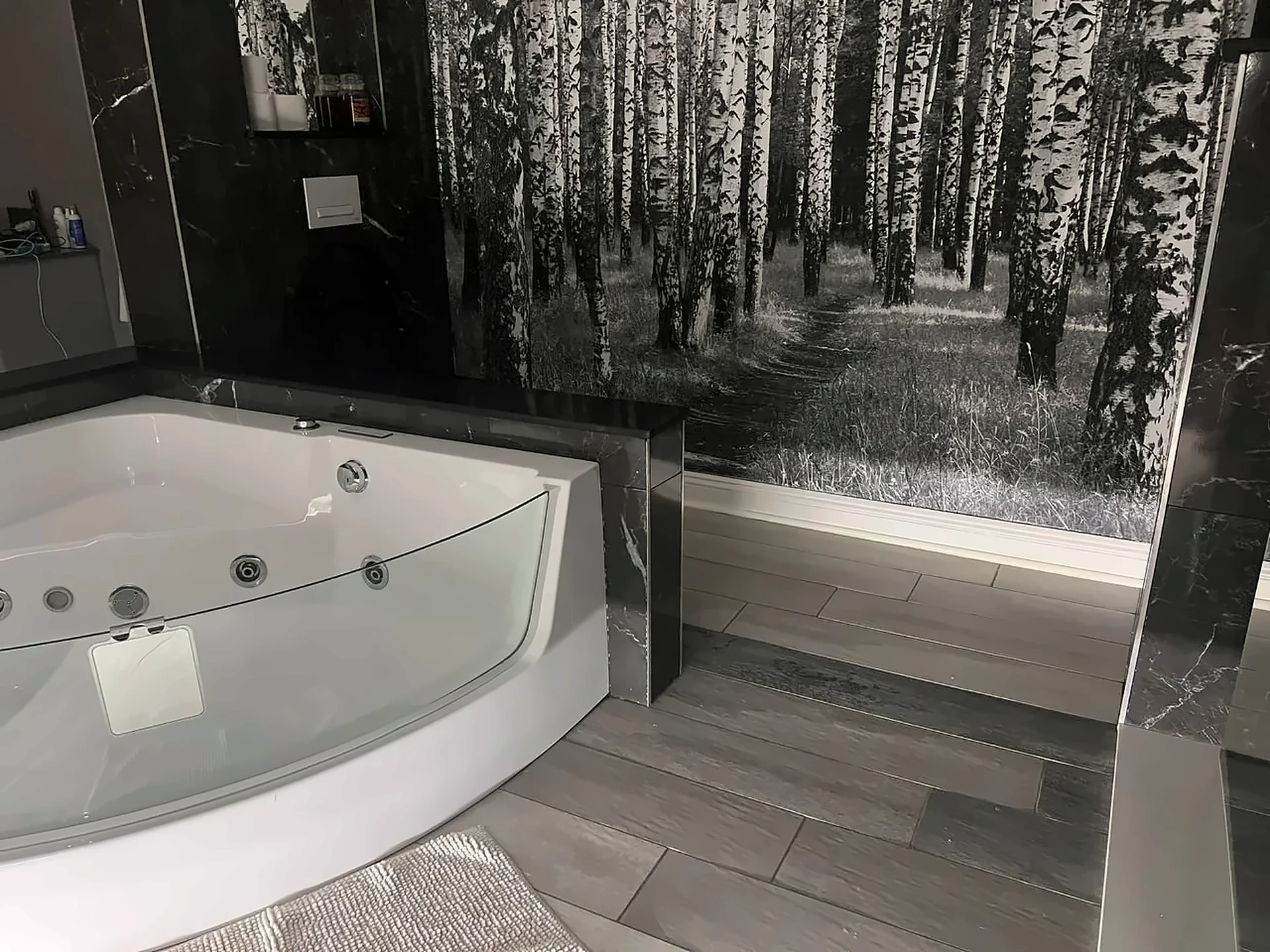 Whirlpool bath set against a black-and-white birch forest wall mural