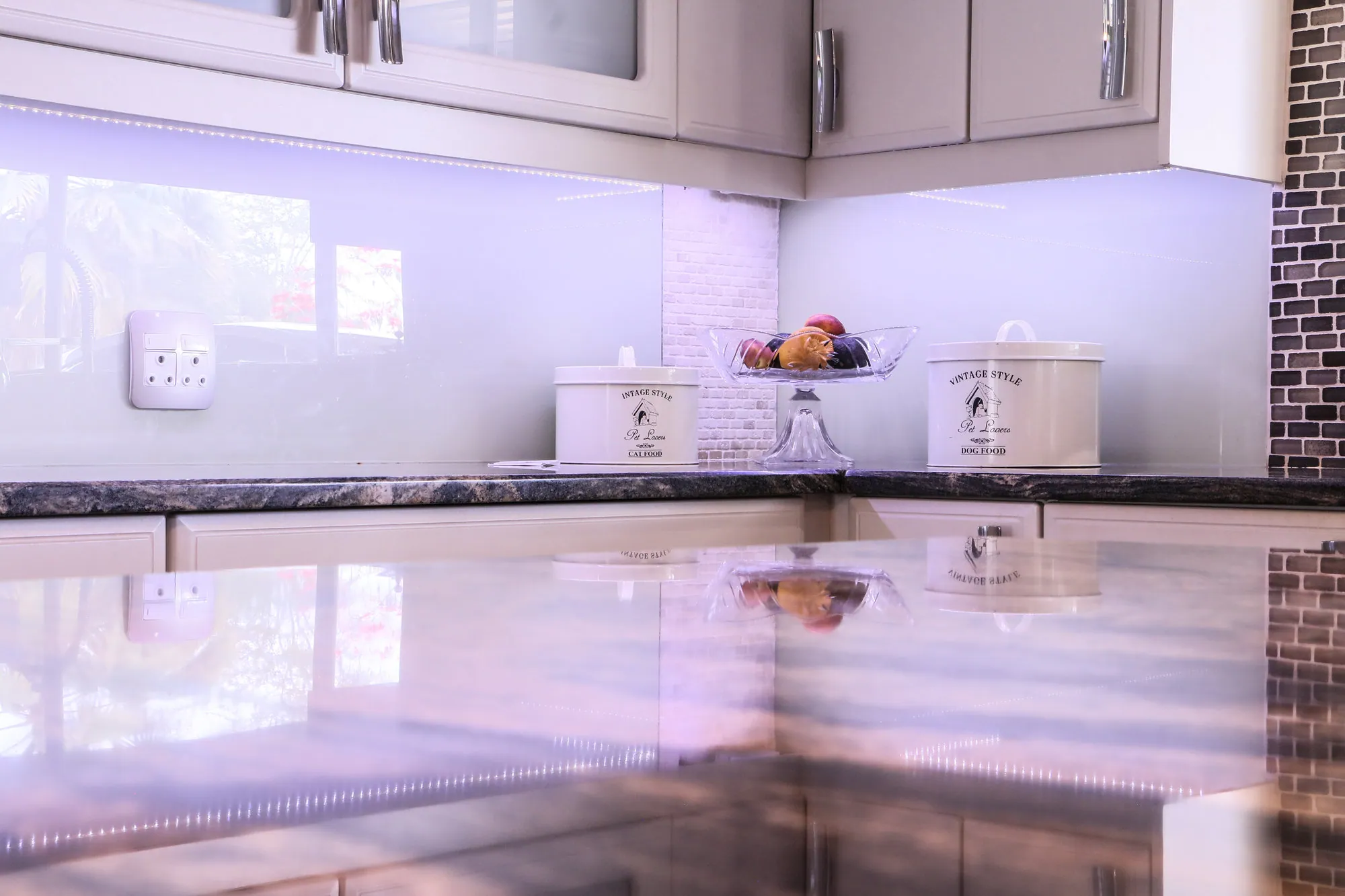 Patterned granite worktop with glass splashback and under-cabinet lighting