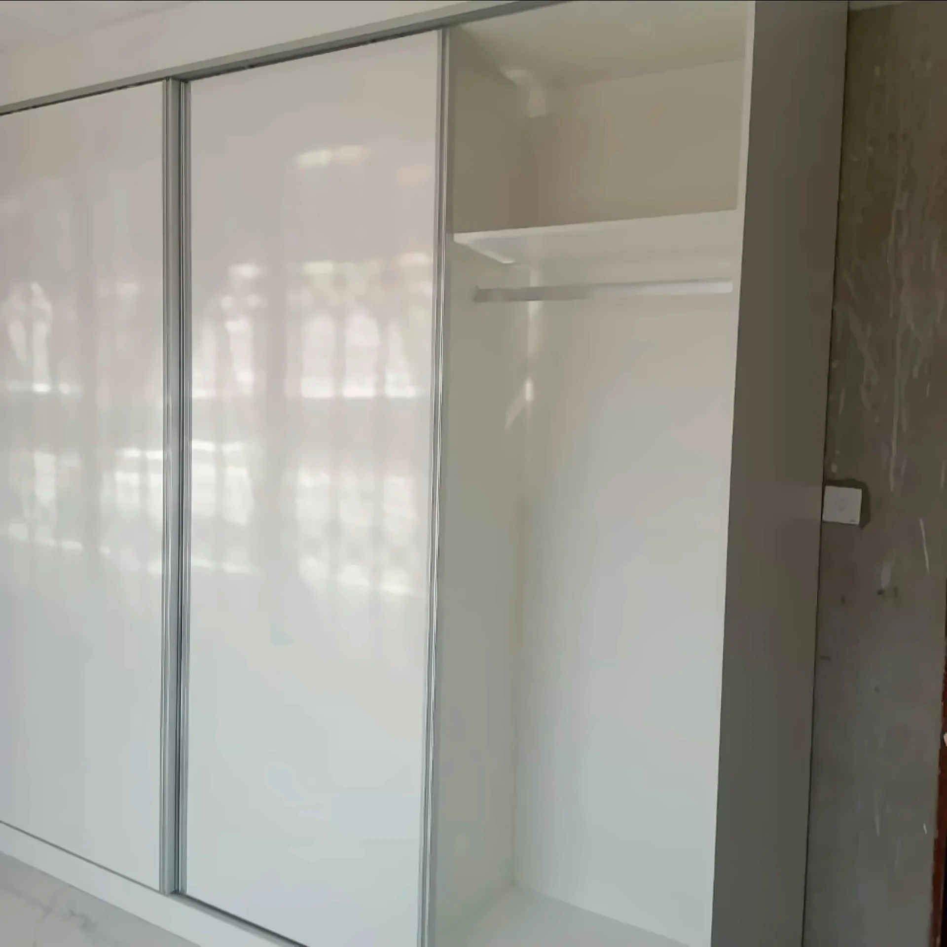 Open white gloss sliding wardrobe showing hanging space