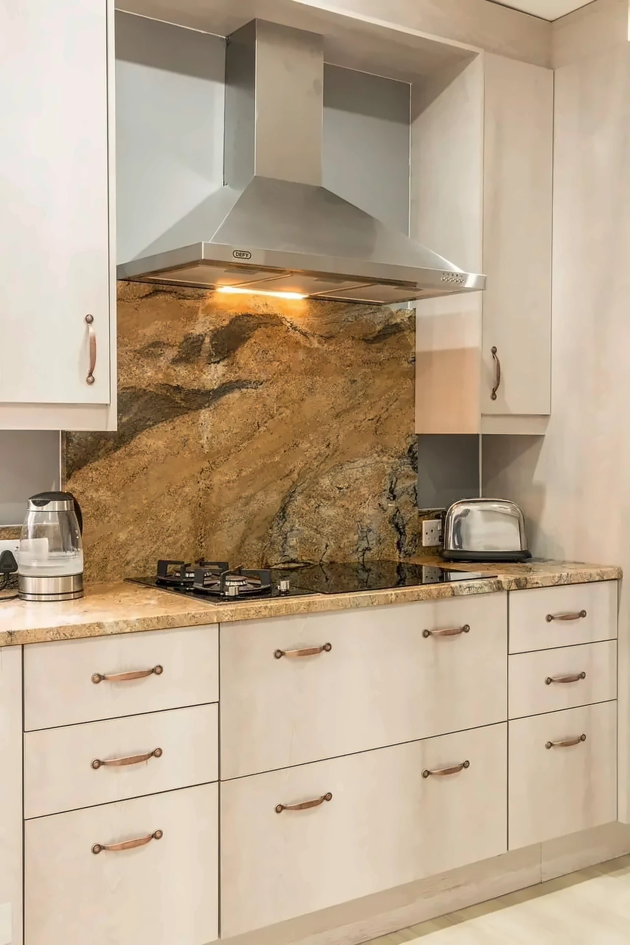 Light timber cabinets with amber stone splashback and stainless extractor