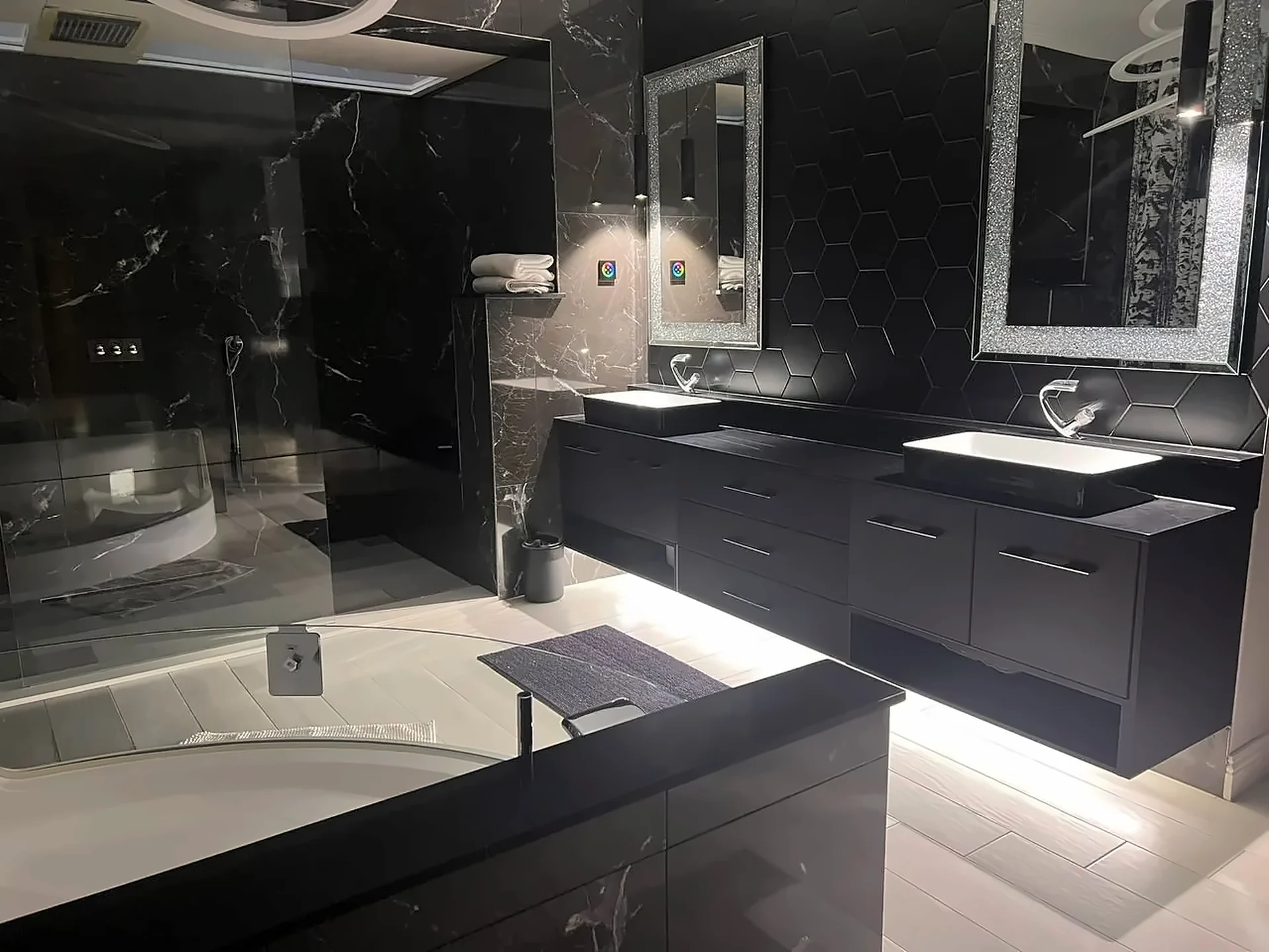Black floating vanity with twin basins and lit mirrors