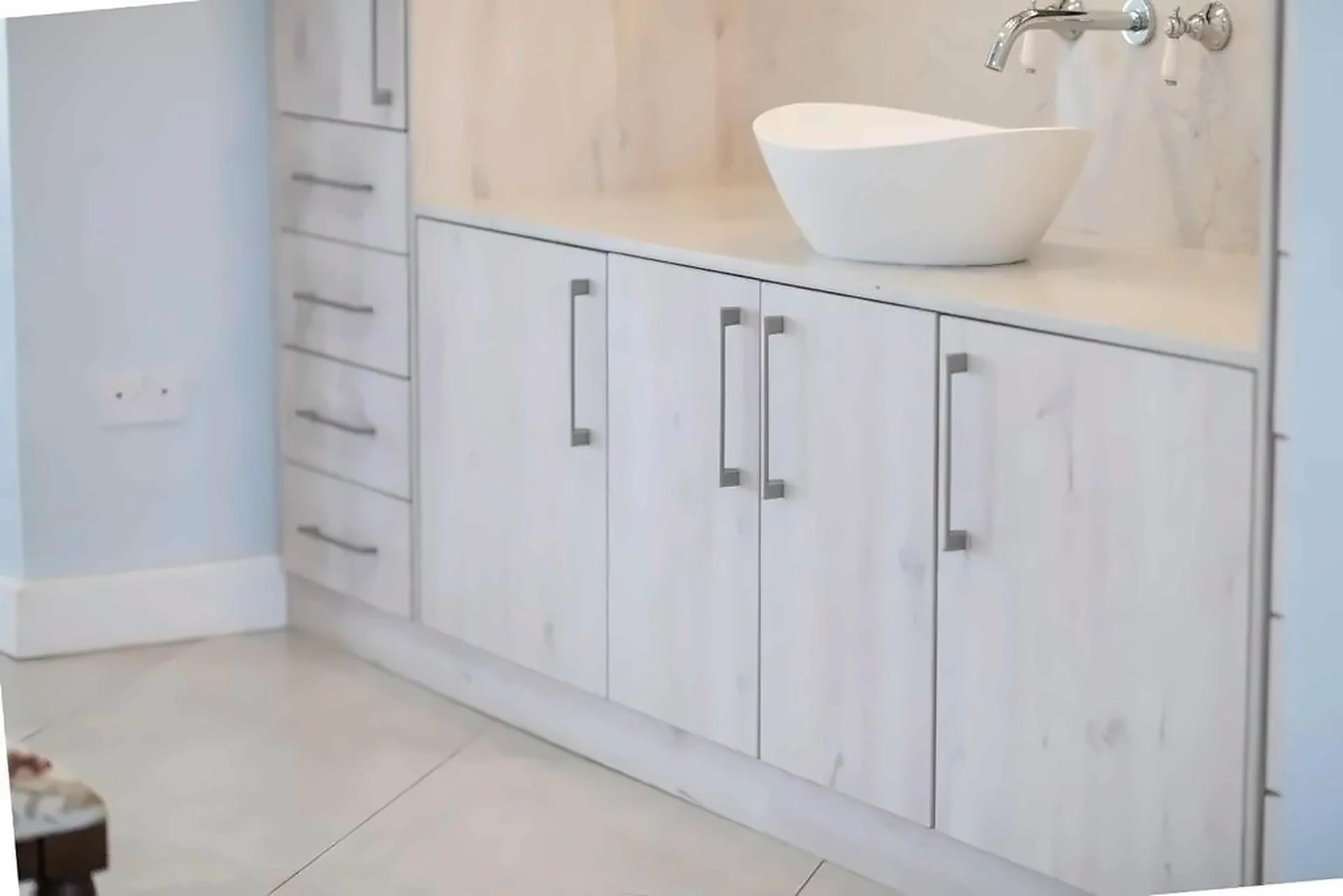Light timber-finish vanity cabinets with white vessel basin