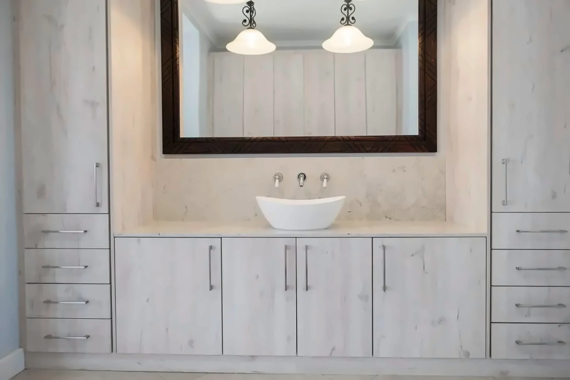 Built-in vanity with vessel basin, tall drawer towers and dark framed mirror