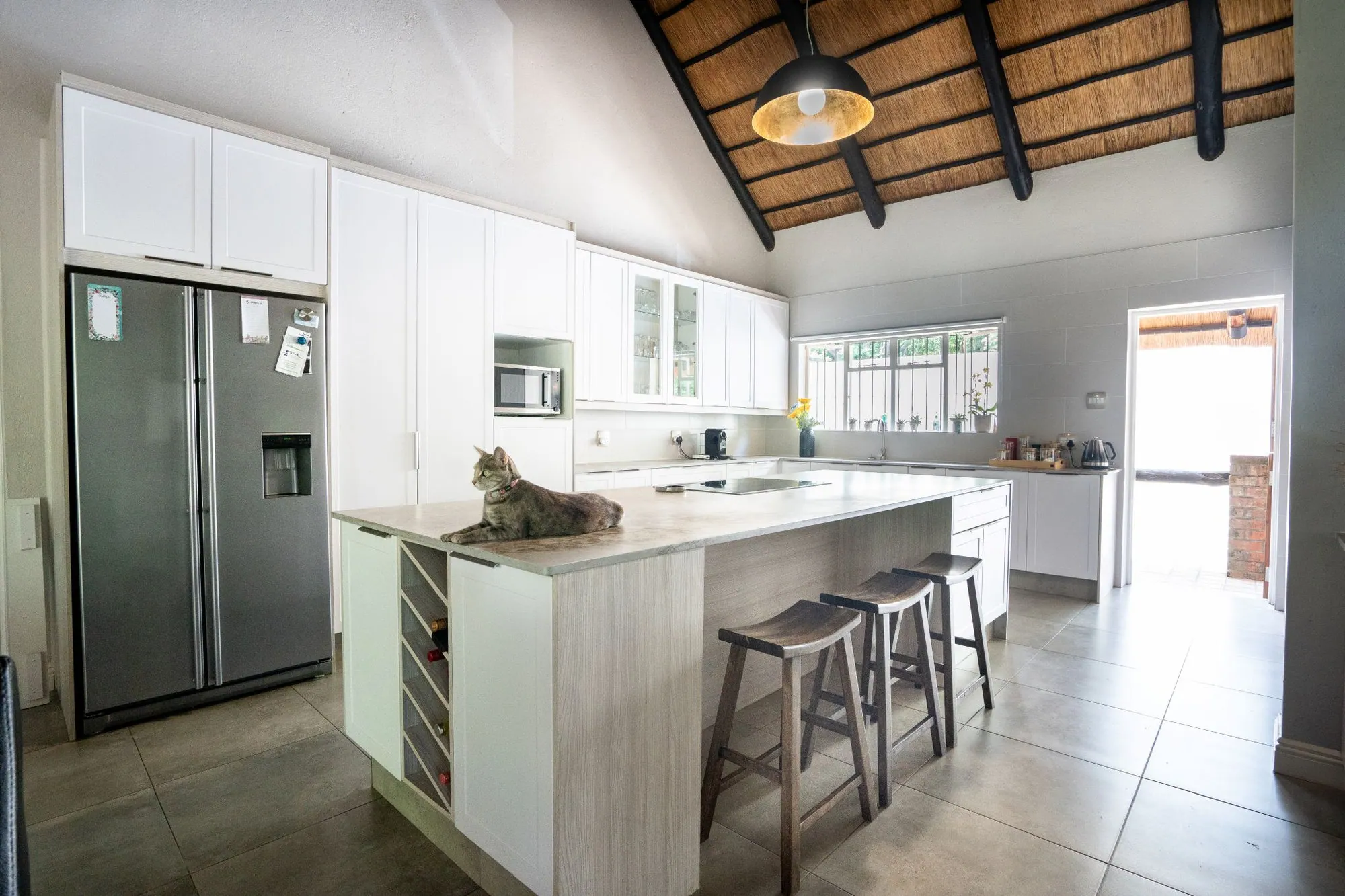 Island kitchen with bar seating beneath a timber roof