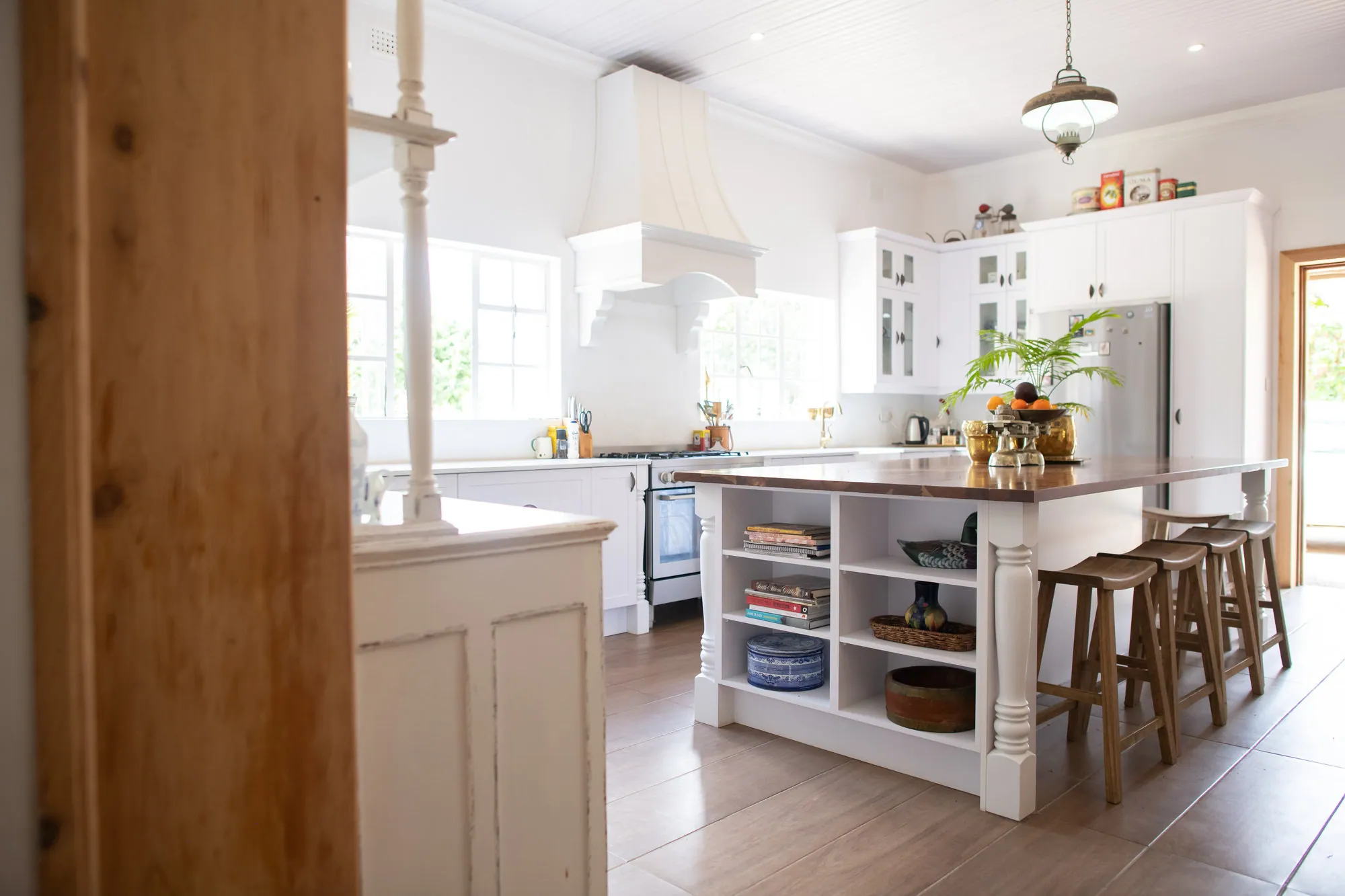 White painted kitchen with a timber-topped island, open shelving and turned legs