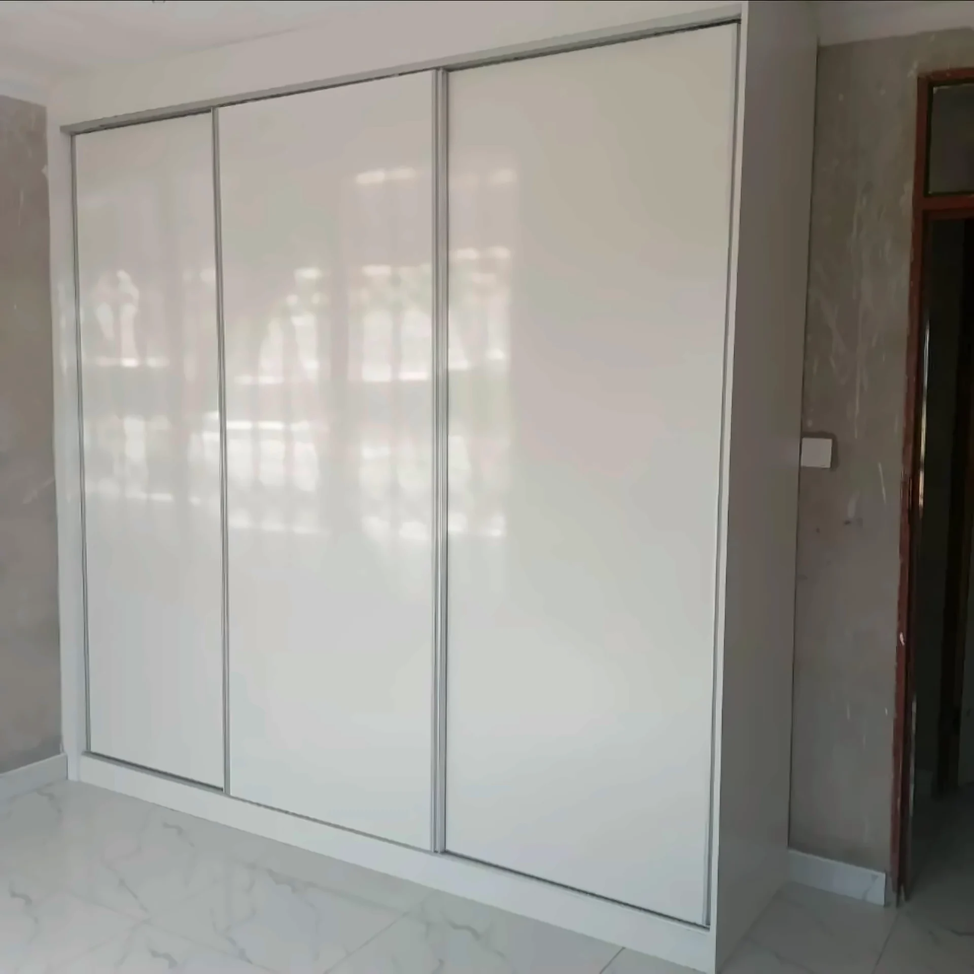 White gloss three-door sliding wardrobe with internal shelving and drawers