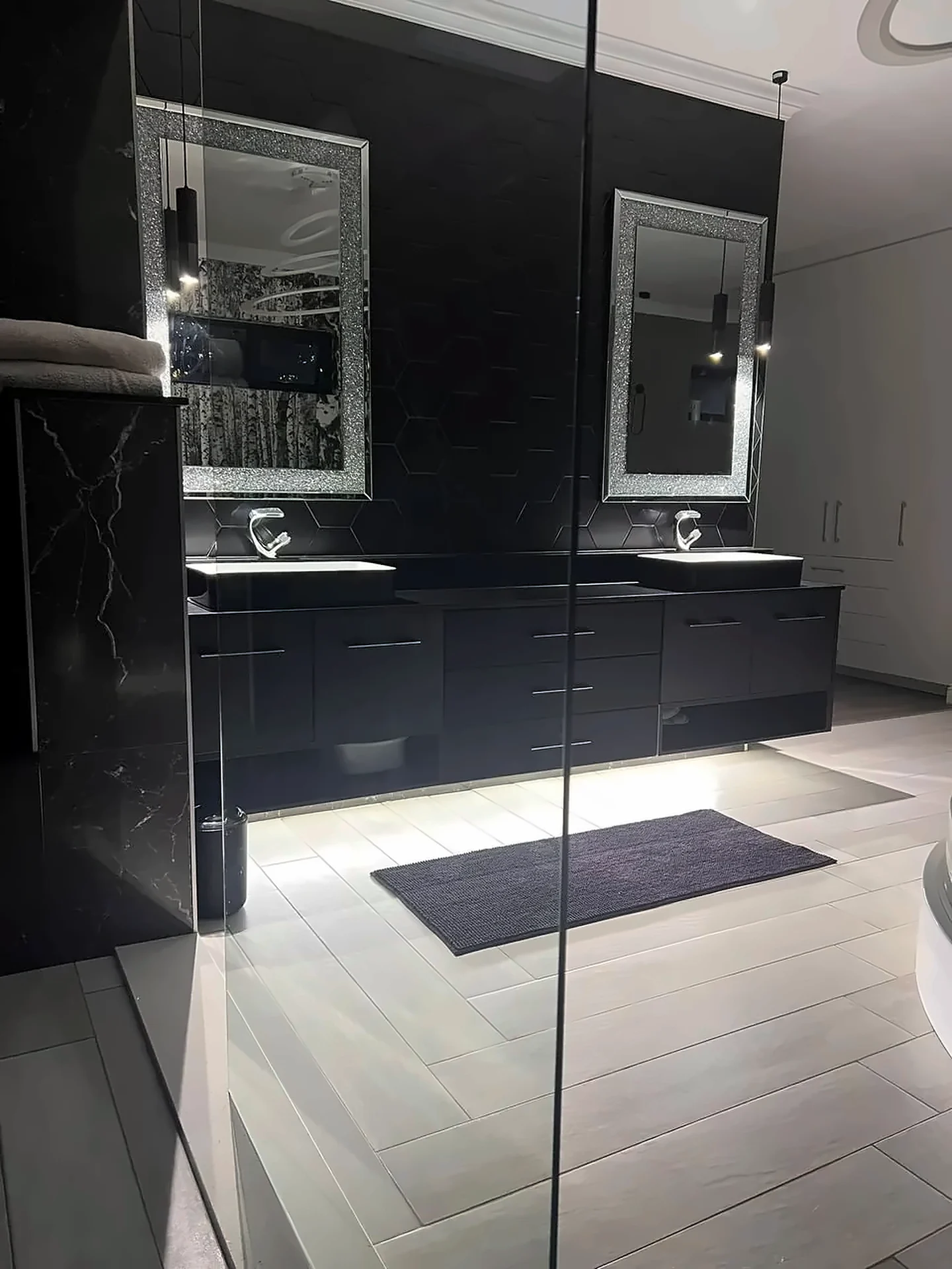 Floating black double vanity with under-lighting and illuminated mirrors
