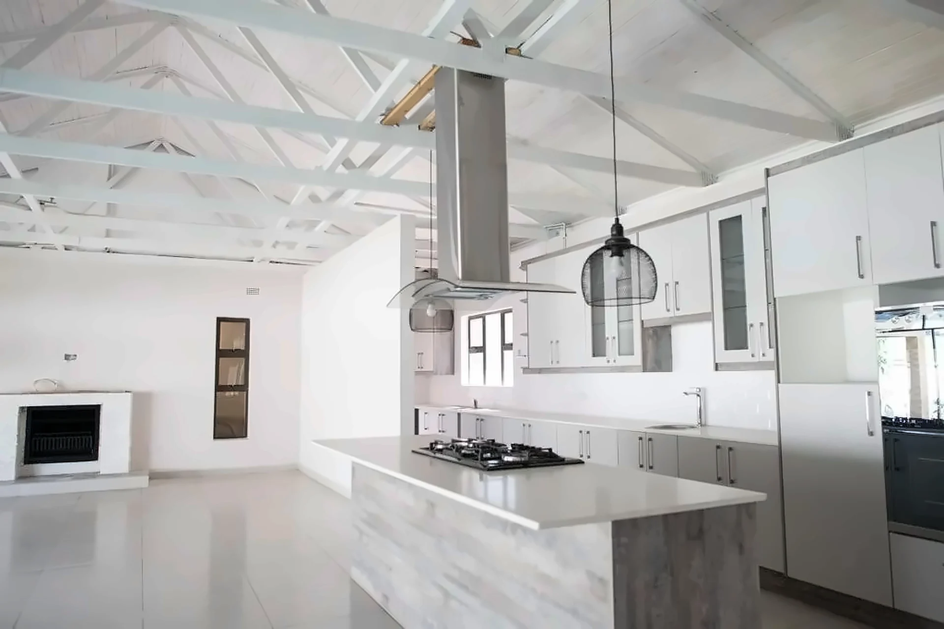 Open-plan kitchen with grey island, stainless extractor and wire pendants