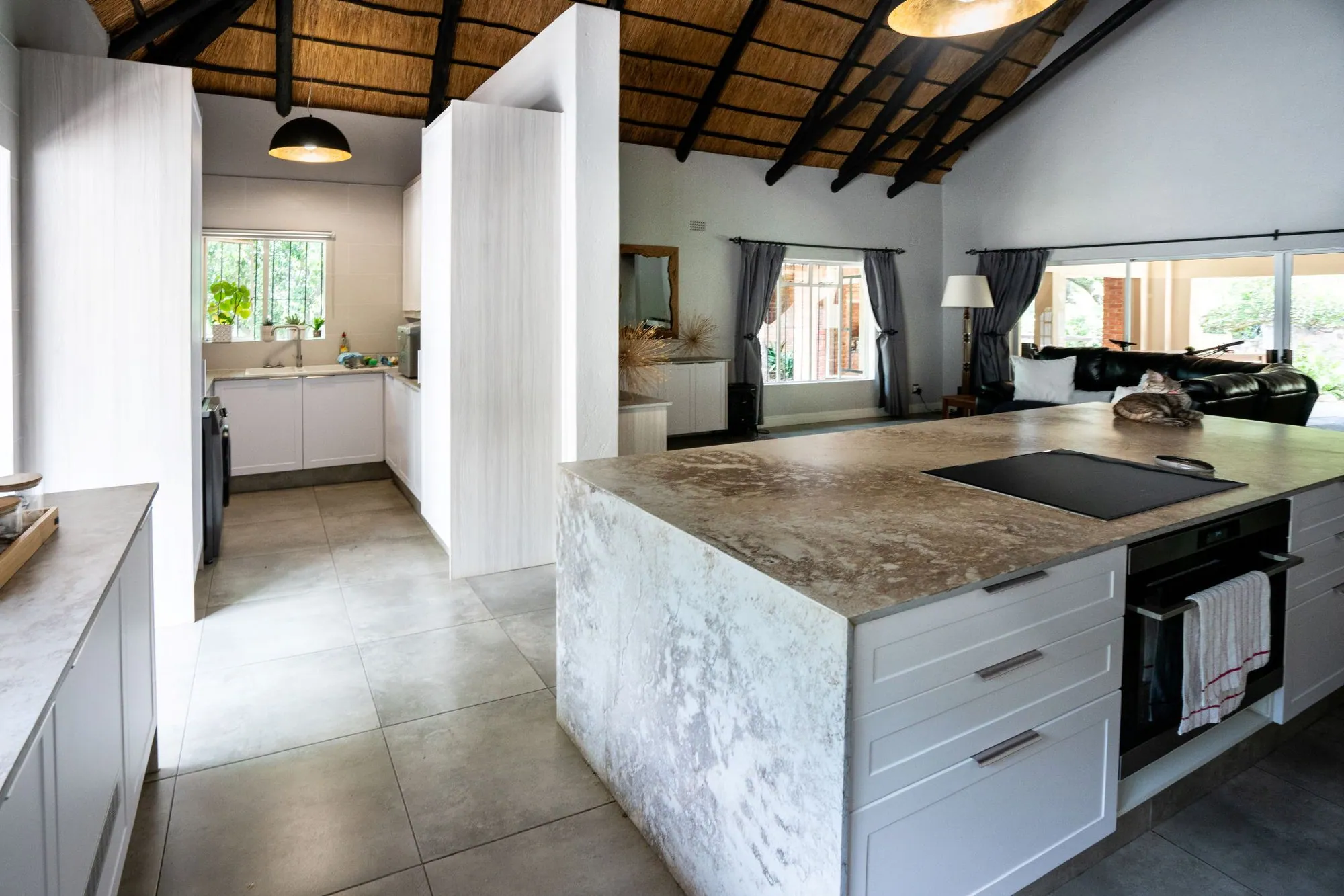 Marble waterfall island with white drawers beneath a thatched roof