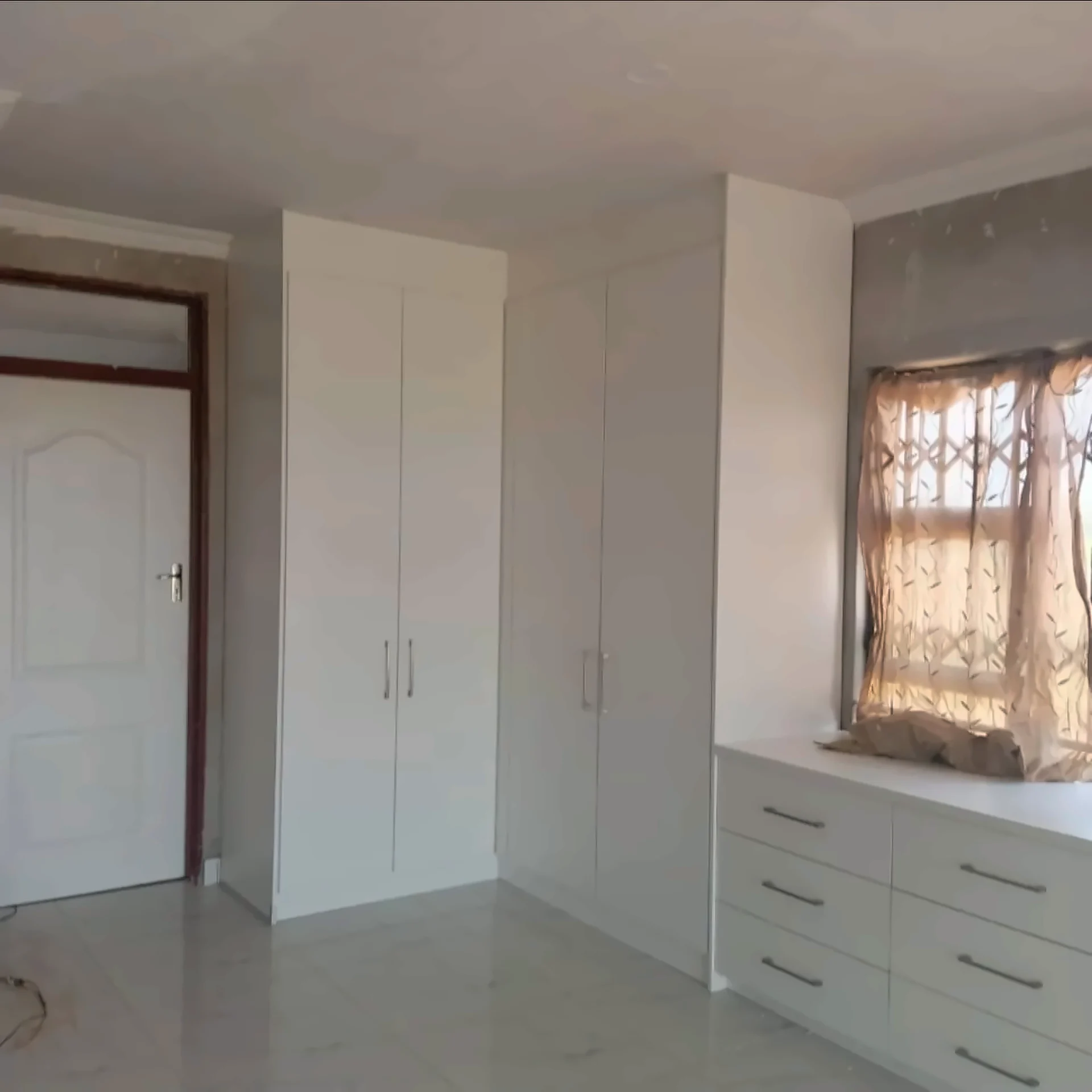 White built-in wardrobes and chest of drawers in a bedroom